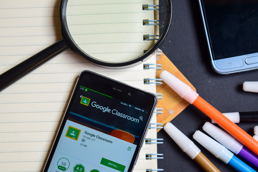 Celular sobre caderno, com aplicativo do Google Classroom aberto